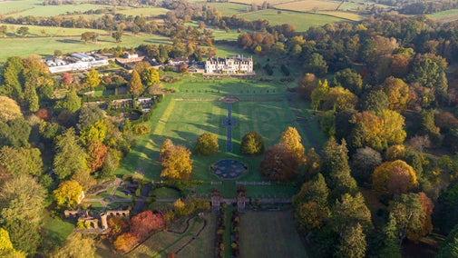 South view of Dyffryn Gardens from above during the autumn, the sun is shining and the leaves are golden